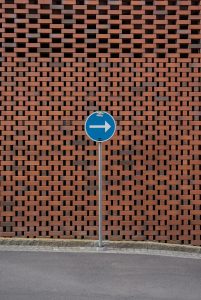 a blue street sign sitting next to a brick wall