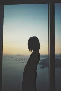 A woman looking out a window at the ocean