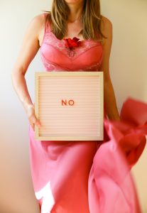 A woman holds a sign that says "no".