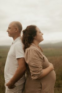 Pregnant woman and man standing back to back outdoors