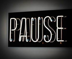 White neon sign spelling the word pause
