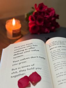 Romantic scene with a candle, roses, and a book.