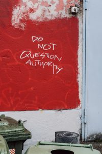 White text on red wall says do not question authority.