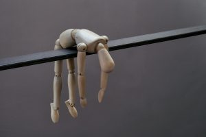 Mannequin doll hangs limply from a dark beam.